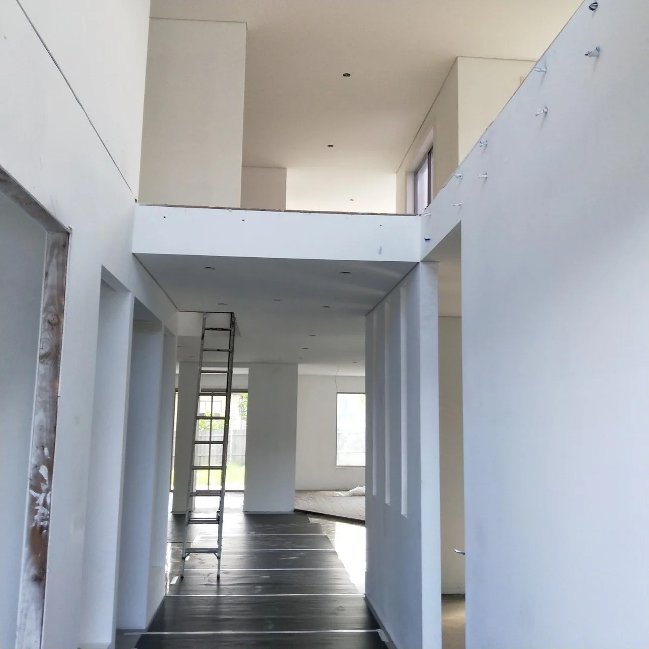 Full home plastering finish — high-ceiling hallway with dark hardwood floor, Northern Beaches build